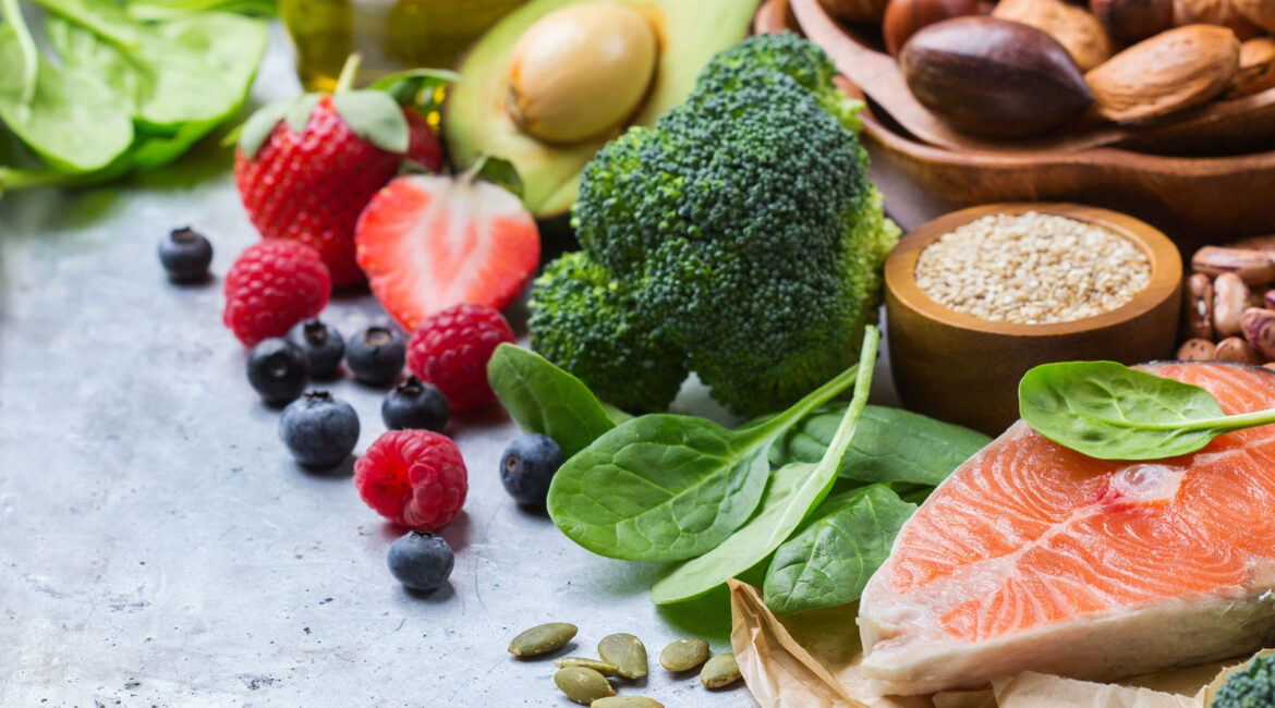 Image depicting a variety of foods beneficial for dental health and a balanced diet, including nuts, salmon, broccoli, and legumes among others