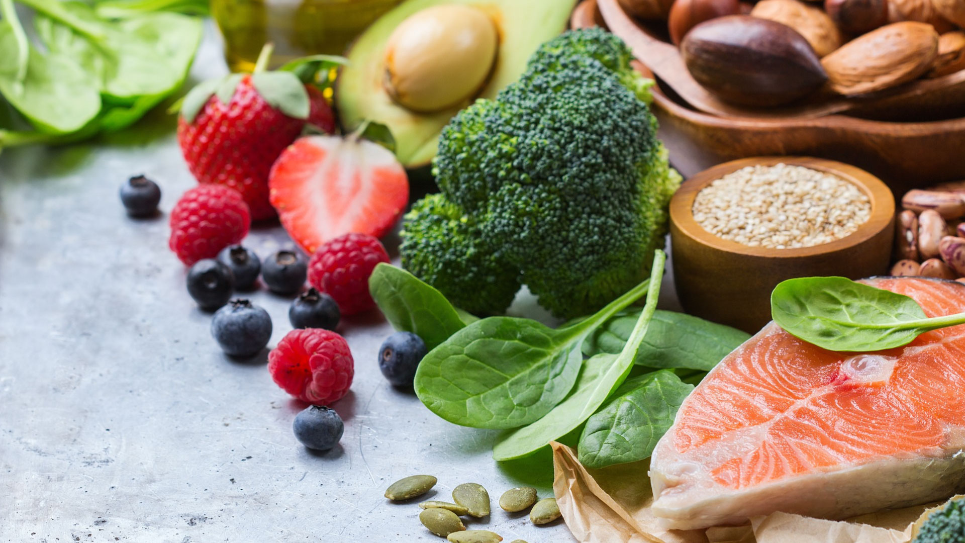 Image depicting a variety of foods beneficial for dental health and a balanced diet, including nuts, salmon, broccoli, and legumes among others