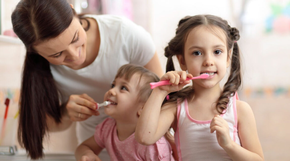 Happy family taking care of their oral hygiene, brushing their teeth together in their home bathroom.