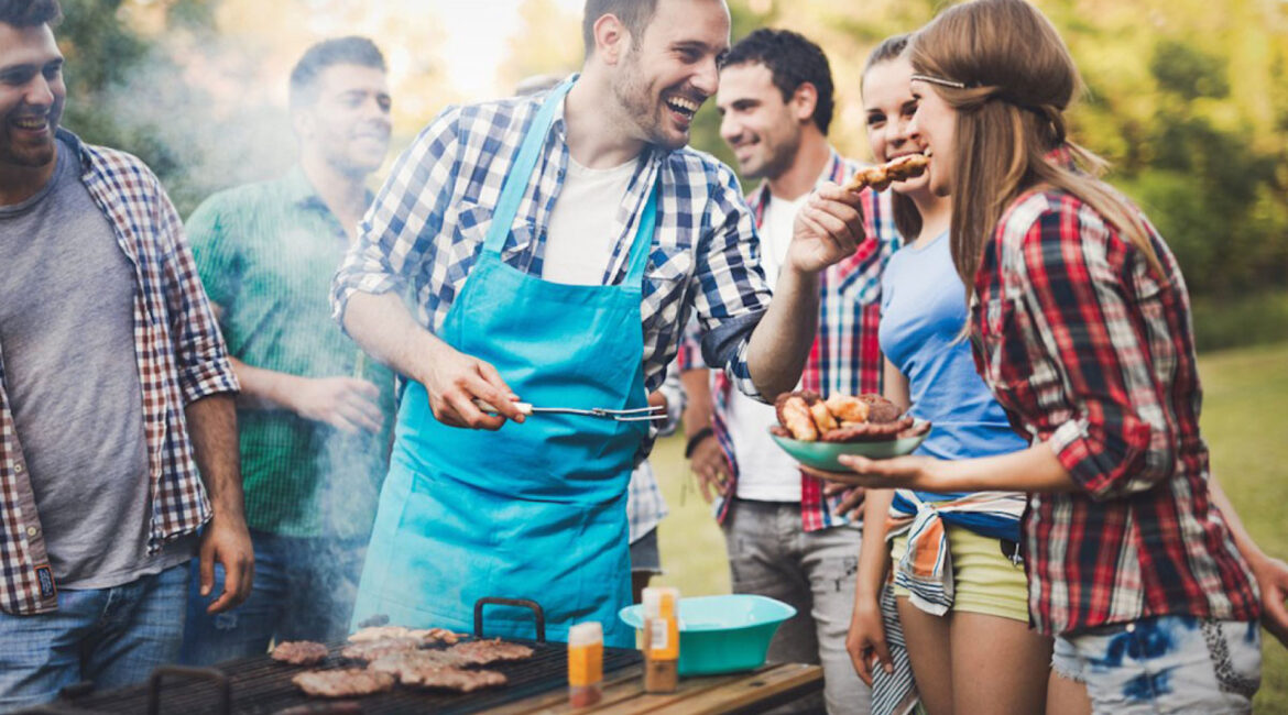 A group of happy people enjoying a summer barbecue, grilling a variety of foods, for Dr. Lenia’s Dental Surgery blog article titled ‘Summer Barbecue: How to Enjoy Grills Without Damaging Teeth