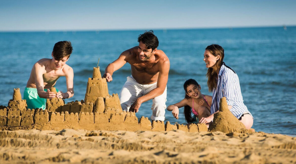 A happy family with children building sandcastles on the beach, all smiling and enjoying a day by the sea. Oral hygiene at the beach.