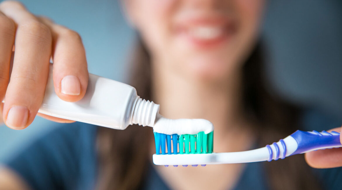 Choosing the right toothpaste: Woman applying toothpaste on a toothbrush. How to Choose the Right Toothpaste for You. Service by Dr. Lenia's Dental Surgery.